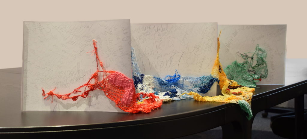 Artwork with crochet and writing in an accordion book.